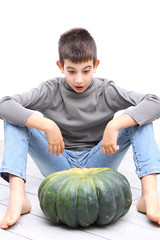 Fototapeta premium Young boy looking surprised at and big pumpkin