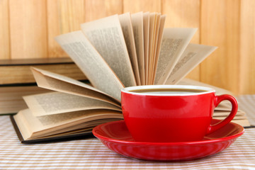 Obraz na płótnie Canvas Cup of coffee and books on tablecloth on wooden background