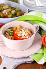 Stuffed tomatoes in pan and bowl on wooden table close-up