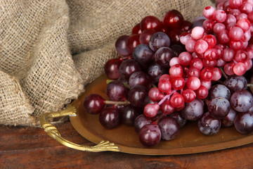 Golden tray with grape on wooden background