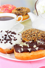 Sweet donuts with cup of tea on table on light background