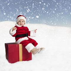 toddler in santa claus outfit sitting on a xmas present in the s