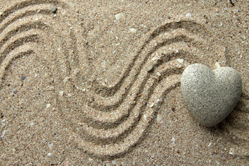 Fototapeta na wymiar Szary Zen stone w kształcie serca, na tle piasku