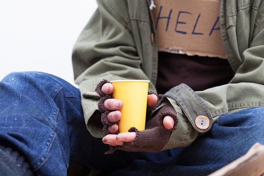 Hands of homeless with a paper cup