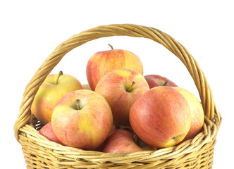 Naklejka na ściany i meble Many red and yellow ripe apples in brown wicker basket isolated