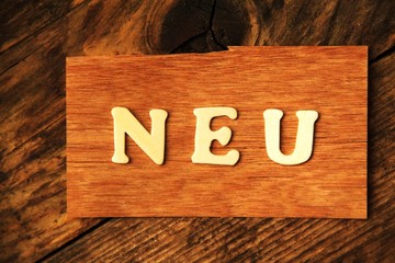 das Wort NEU auf Holztafel