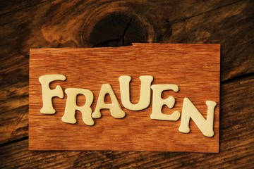 das Wort FRAUEN auf Holztafel