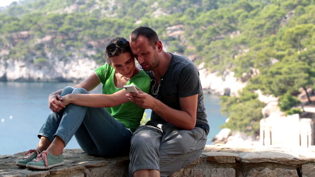 Young couple with smartphone in beautiful nature scenery