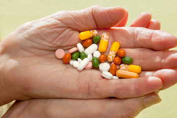 Cocktail of pills and tablets in an elderly hand.