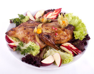 гусь фаршированный на тарелке с яблоками и зеленью