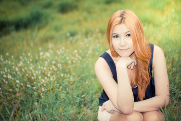 Beautiful young asian woman on the green meadow with white flowe