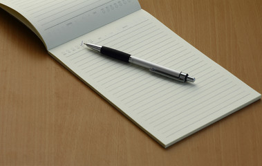 Pen and business plan notebook on wooden desk
