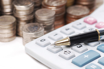 Old dusty ball pen on calculator with stack coins background