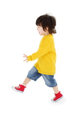 Little boy in yellow shirt walks isolated on white