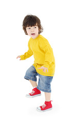 Little boy in yellow shirt stands and warily looks away isolated