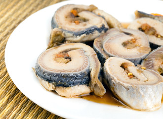 Rolls from a herring on a plate, on a straw support