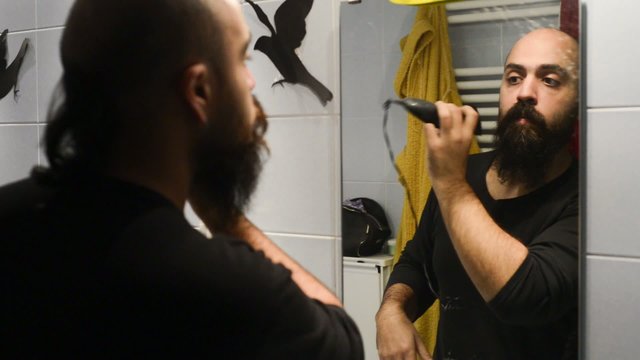 long beard and mustache man shaving in bathroom