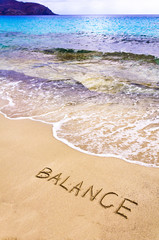 Fototapeta premium Word BALANCE written on sand, with sea waves in background