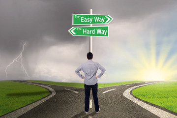 Businessman looking at sign of easy vs hard way