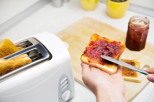 Preparing toast with jam for breakfast