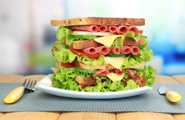 Huge sandwich on wooden table, on light background