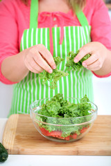 Happy smiling woman in kitchen preparing vegetable salad
