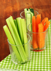 Fresh green celery with vegetables in glasses on table close-up