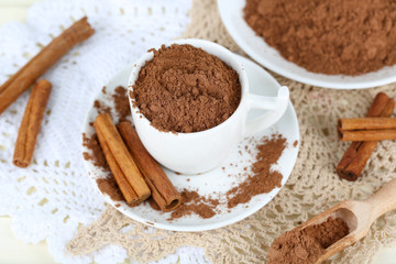 Cocoa powder in cup on napkin on light background