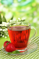 Delicious strawberry tea on table on bright background