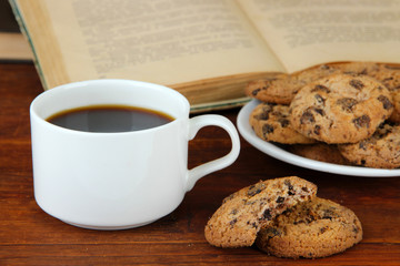 Cup of coffee with cookies and books on wooden background