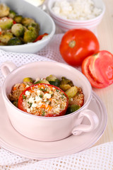 Stuffed tomatoes in pan and bowl on wooden table close-up