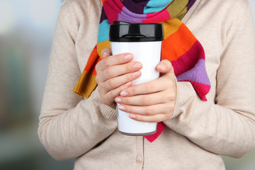 Hot drink in plastic glass in hands on bright background