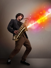 Young man playing on saxophone with colorful sound waves