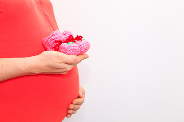 Pregnant woman holding pink baby shoes on her belly