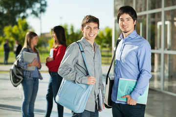 Male Students With Friends Standing In Background On Campus