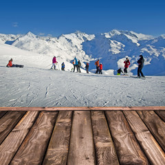 Skieurs sur une piste de ski, terrasse en bois