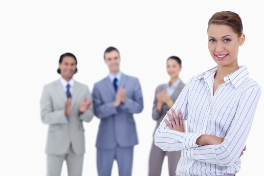 Close-up of a woman crossing her arms with business people appla