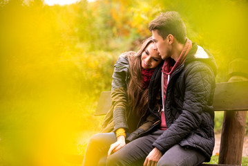 Obraz premium Loving couple in the autumn park sitting on a bench