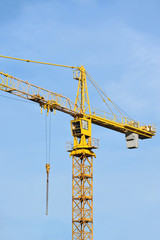 Yellow construction tower crane against blue sky