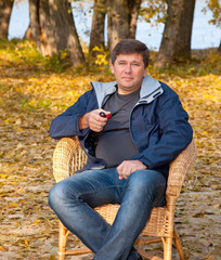 Obraz premium man sitting in a cane chair and smoking a pipe