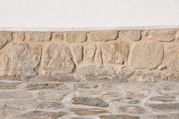 Pedestrian walkway in front of old stone wall