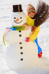 Winter fun, happy kid playing with snowman