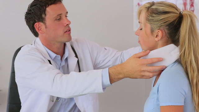 Doctor fitting a neck brace on his patient