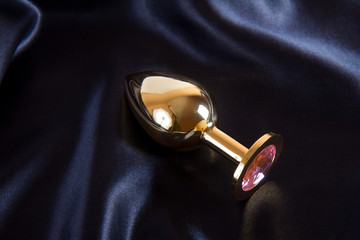 Golden butt plug sex toy on black