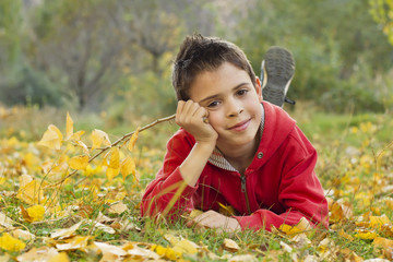 Niño tendido en el suelo cubierto de hojas otoñales