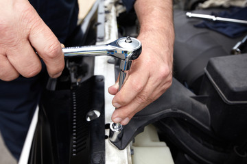 Hands of auto mechanic with wrench.