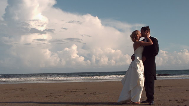 Happy newlywed couple kissing on the beach