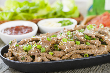 Bulgogi - Korean grilled beef with side dishes and lettuce