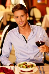 Handsome young man with glass of red wine in restaurant