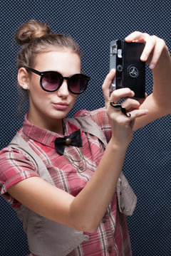 Portrait of trendy girl shooting autoportrait with retro camera